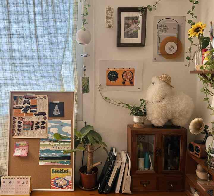 ヴィンテージ調のブラウン色が基調の小さな作業スペース。植物やポスターが並び、青のチェック柄カーテンが印象的なインテリア