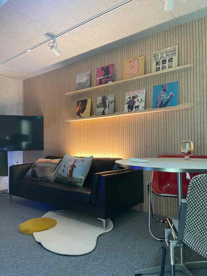 ミッドセンチュリーモダンスタイルのリビング、黒いソファと白い丸テーブル、壁棚にアートが配置された空間