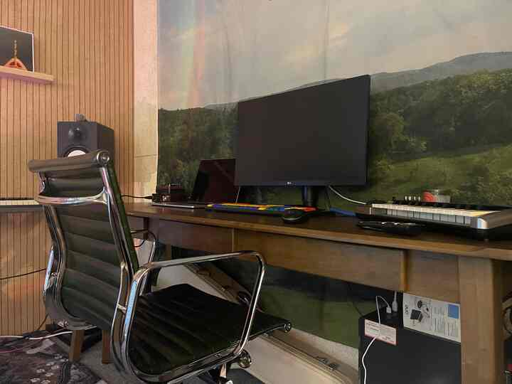 ナチュラルウッドトーンと深いグリーンのホームオフィス、広めのデスクとオフィスチェアが配置された落ち着いた作業空間