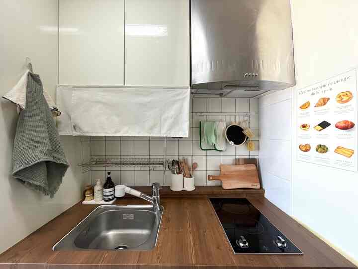 白と木目調が調和したコンパクトなキッチン、収納カバーやカッティングボード、キッチン小物が配置された清潔感のあるインテリア