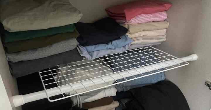 白い圧縮棒とメッシュネットで整理されたクローゼットの収納スペース