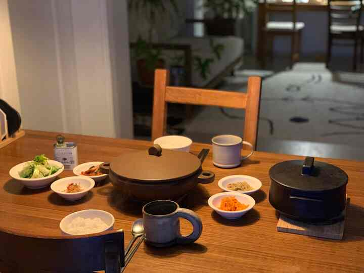 温かみのある木目調のキッチンダイニング、伝統的な鍋とシンプルな食器が配置された落ち着いた雰囲気のインテリア