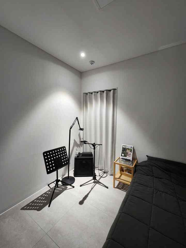 ナチュラルカラーと黒が調和した一人用寝室、音楽機材が配置されたモダンでコンパクトな空間
