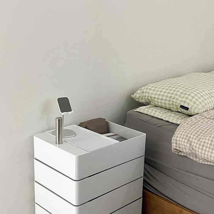 ホワイトとグレーのトーンの寝室、チェック柄の寝具とナイトテーブルが配置された清潔感のあるモダンなインテリア