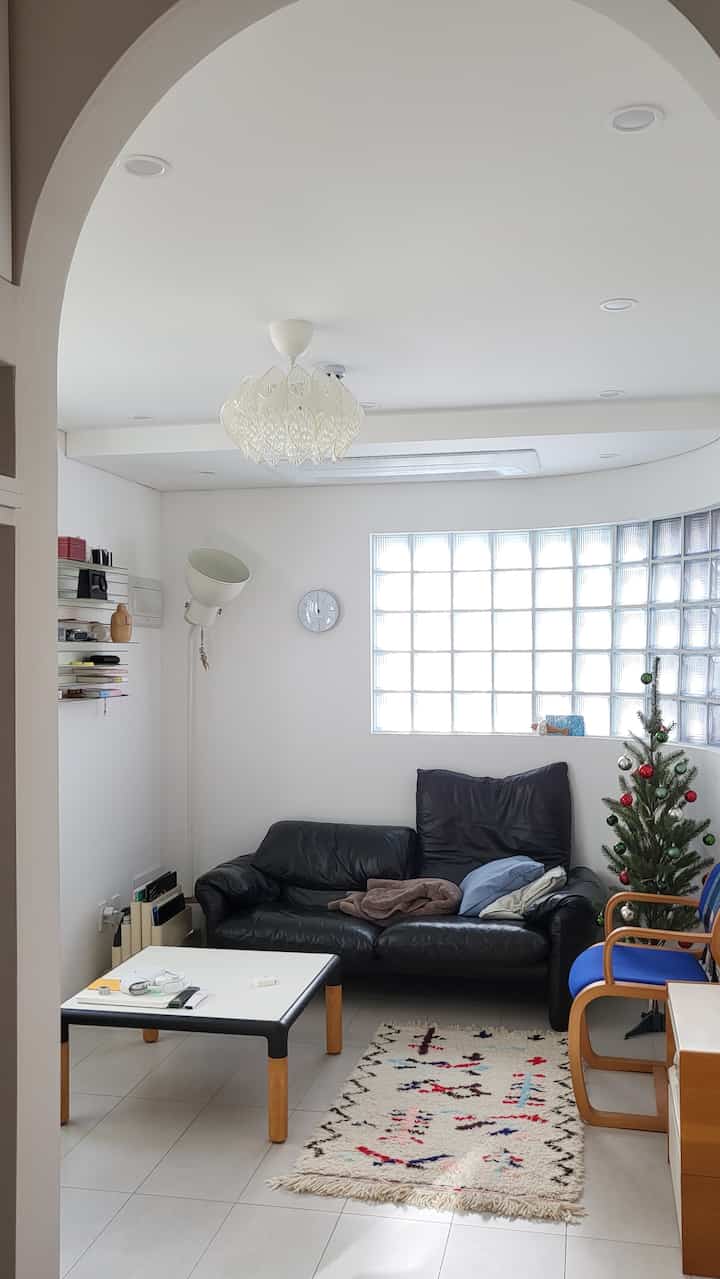 白い壁と黒い革のソファが配置されたヴィンテージ風リビング、クリスマスツリーと多彩な小物が温かみのある空間を演出