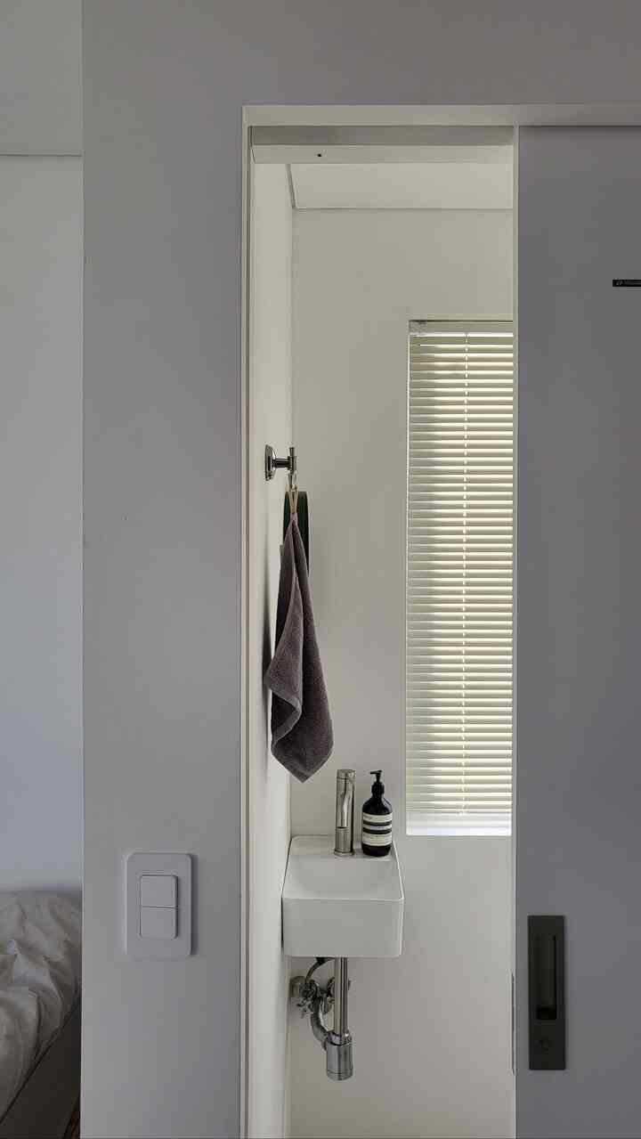 白を基調とした乾式トイレ、コンパクトな洗面台とタオルが配置されたミニマルで清潔感のあるインテリア