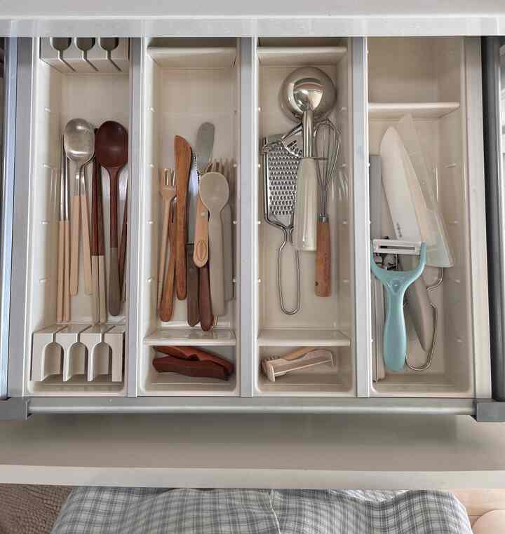キッチンの引き出しにある白いカトラリートレイに木製とステンレス製のカトラリーが整然と並べられた印象的な空間
