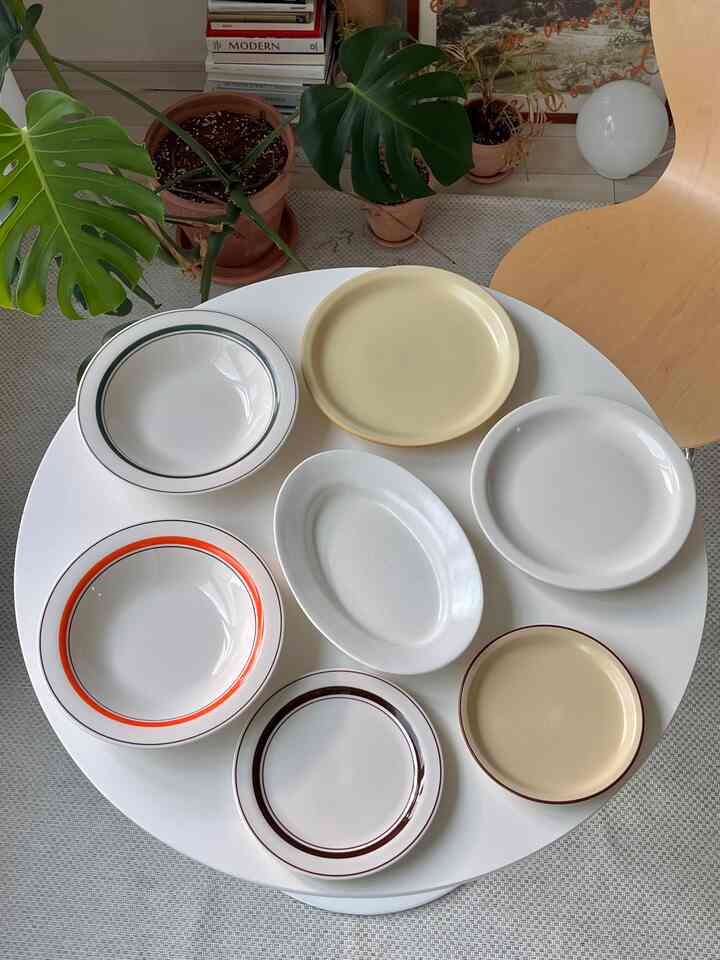 ホワイトとベージュのトーンの丸テーブルにさまざまな皿が置かれたキッチンダイニングスペース