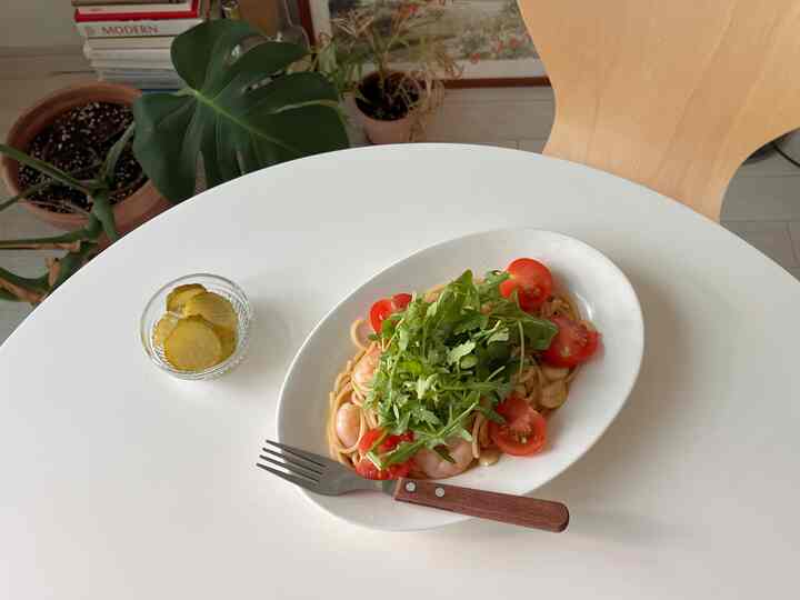 白とナチュラルカラーのダイニング空間、木製チェアと観葉植物が配置された清潔感と自然な雰囲気のあるインテリア