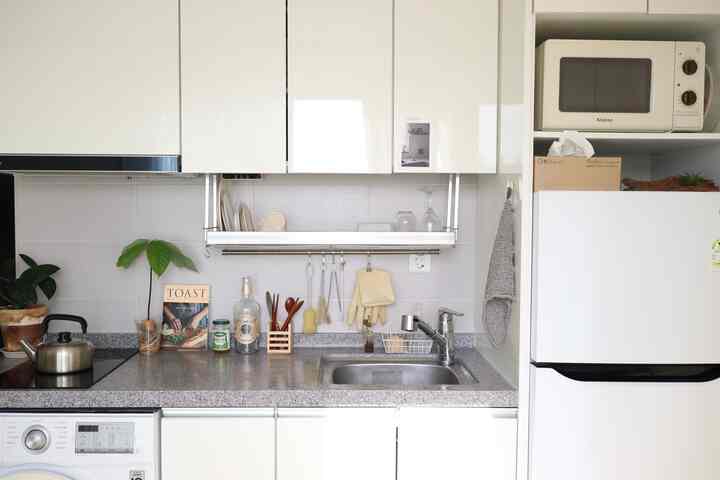 白を基調としたキッチン空間、シンクや調理器具が整然と配置されたミニマルでナチュラルな雰囲気のインテリア