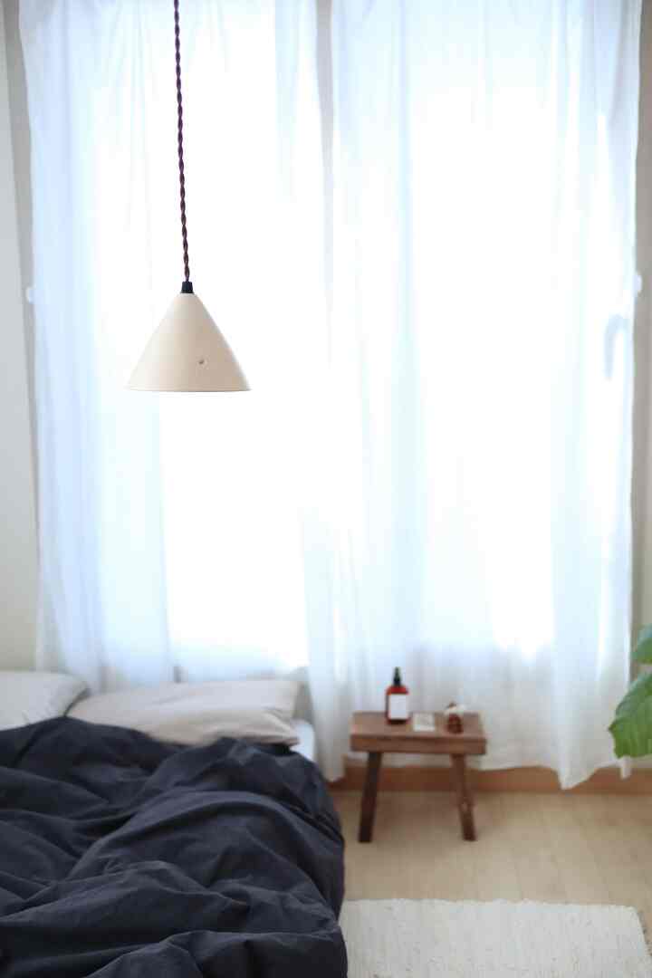 ホワイトとナチュラルカラーの寝室、ペンダントライトとシンプルな家具が配置された落ち着いた空間