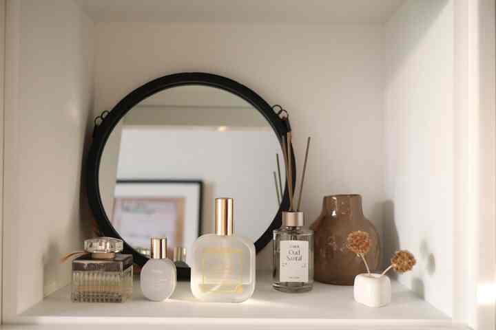 白を基調とした玄関の靴棚に黒い丸い鏡、香水、ディフューザー、陶器の花瓶、ドライフラワーが配置された雰囲気のあるインテリア