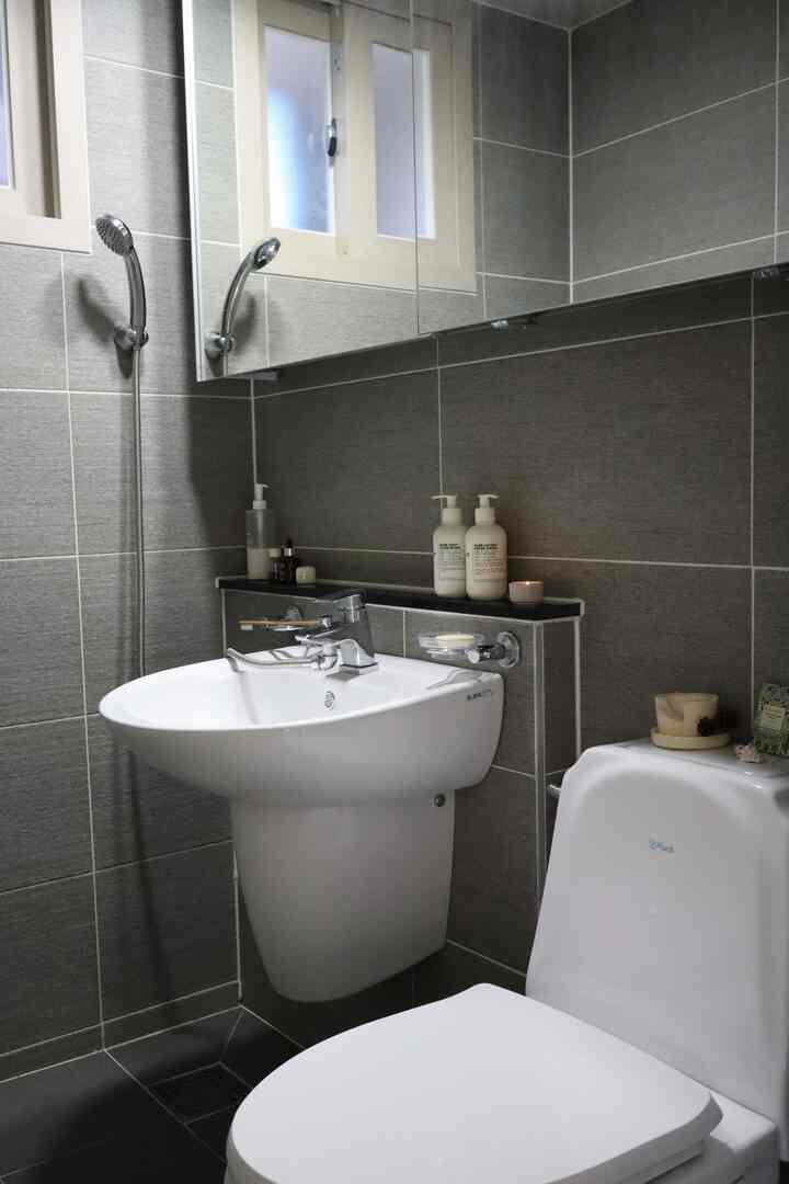 ブラックとグレーのトーンでまとめられた清潔感のあるトイレ、白い洗面台と便器が配置されたシンプルな空間