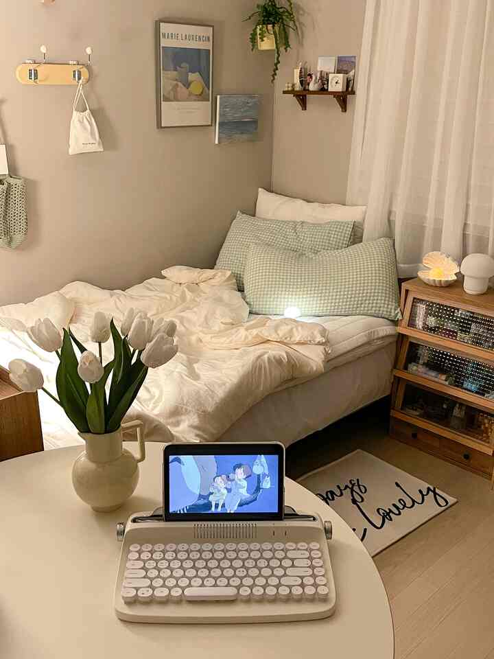 ホワイトとナチュラルカラーのコンパクトな寝室、シングルベッドと丸テーブルにタブレットとキーボードが置かれた温かみのあるインテリア