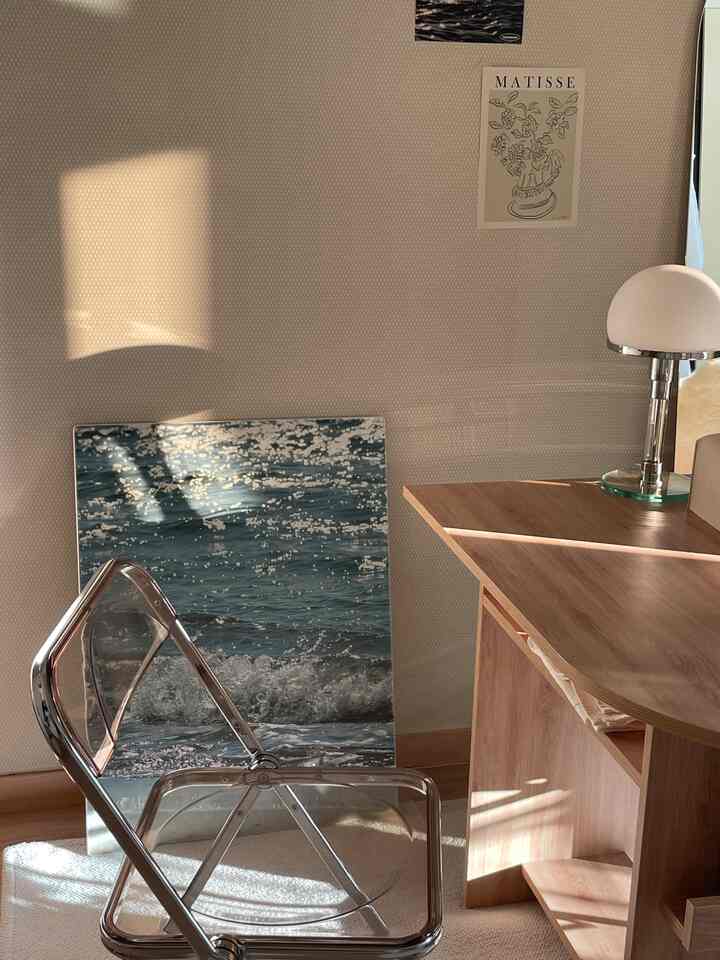 柔らかな木目調と透明な椅子が配置されたコンパクトなホームオフィス空間、自然光に包まれた落ち着いた雰囲気のインテリア