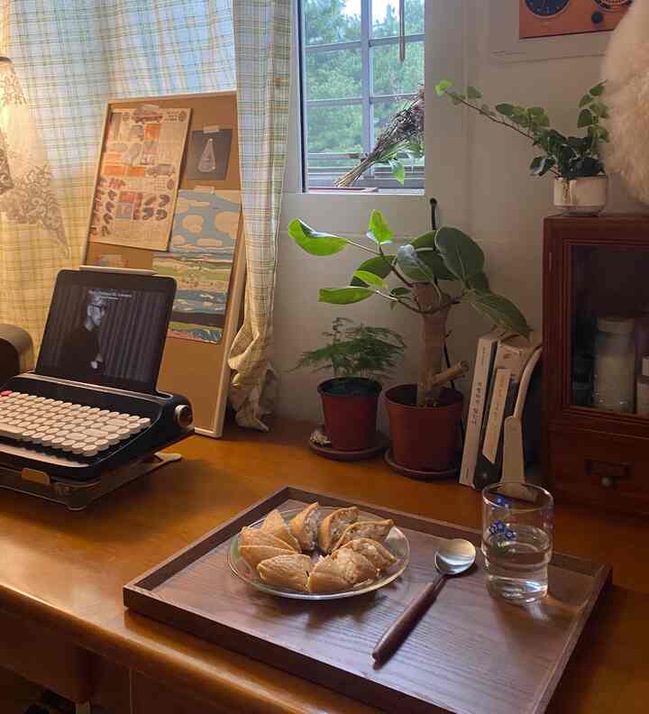 温かみのあるブラウンの木目調と白い壁が調和した雰囲気のある書斎、ヴィンテージタイプライターと植物が置かれたデスク