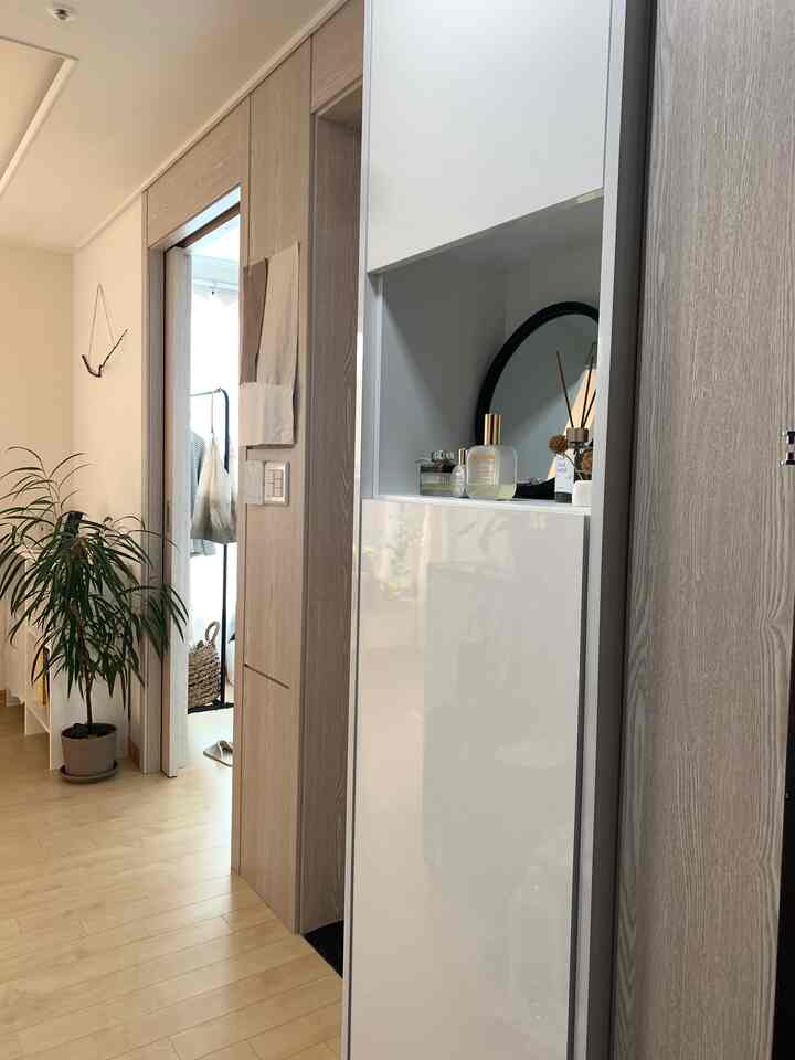 ナチュラルな木目調と白が調和する玄関スペース、化粧台と観葉植物が配置された清潔感のある明るいインテリア