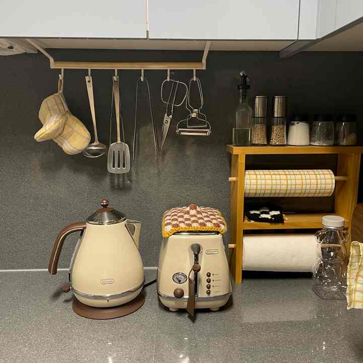 黒とベージュの色調のキッチン、調理器具と電気ケトル、トースターが配置された現代的な雰囲気のインテリア