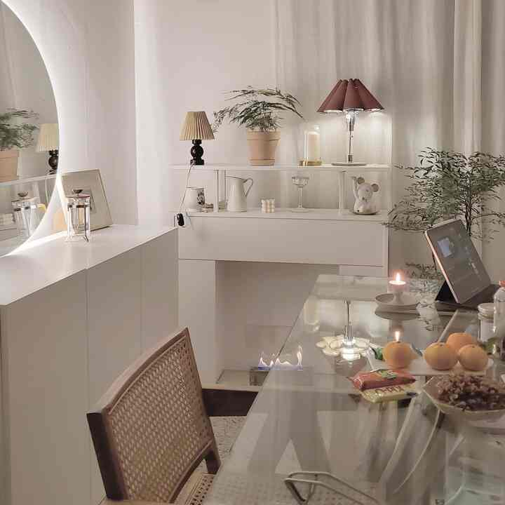 アイボリーとナチュラルトーンのリビング、ラタンチェアと透明なガラステーブルが配置された、雰囲気のあるヴィンテージ空間