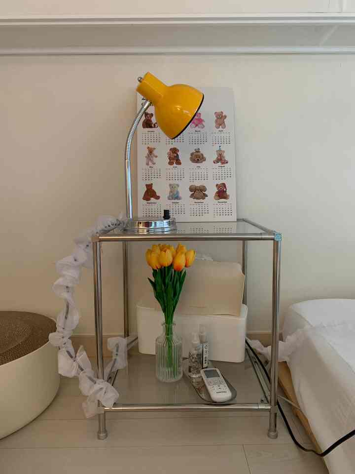 明るいホワイトトーンの壁と床に黄色い照明がある寝室のサイドテーブルスペース