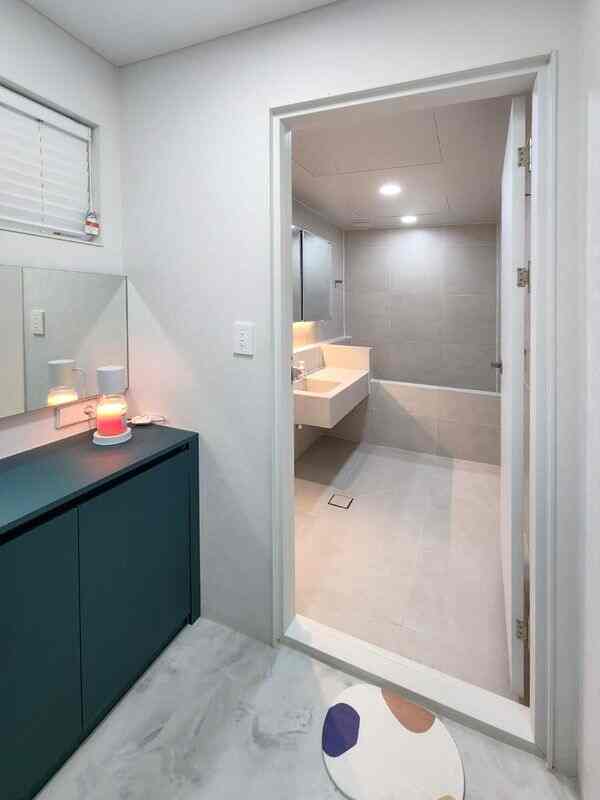 ホワイトとダークグリーンの色調が特徴の狭い玄関とバスルーム、ミニマルでモダンなデザインの印象的なインテリア