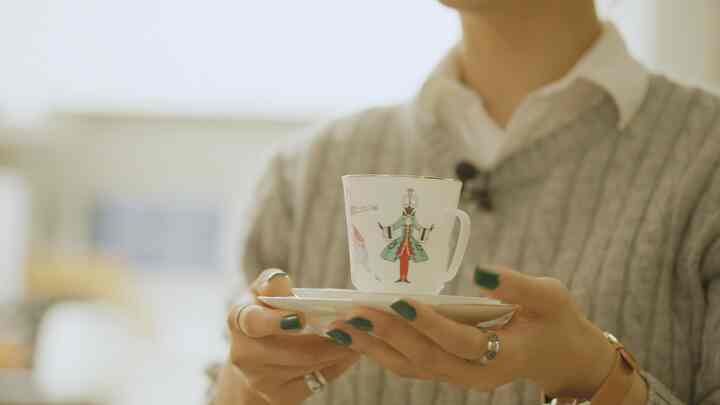 白い地にバレエ衣装の模様が描かれたティーカップとソーサーを手に持つ様子が中心のインテリア