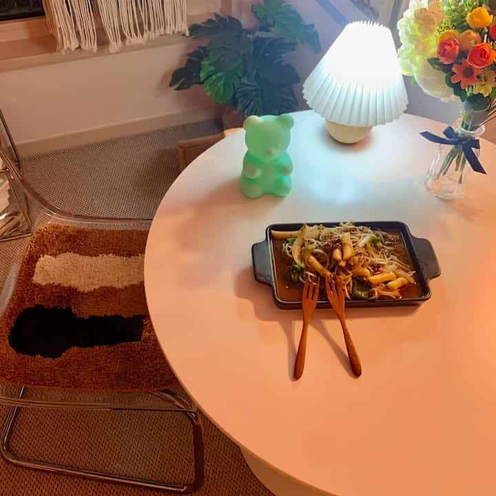 暖かいブラウンとホワイトの色調の円形の部屋、丸テーブルにムードランプと花瓶が置かれた雰囲気あるおうちカフェの空間