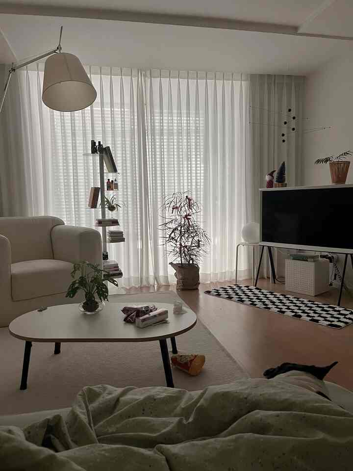 明るい白を基調としたリビング、ソファとコーヒーテーブル、テレビが配置された雰囲気のあるインテリア