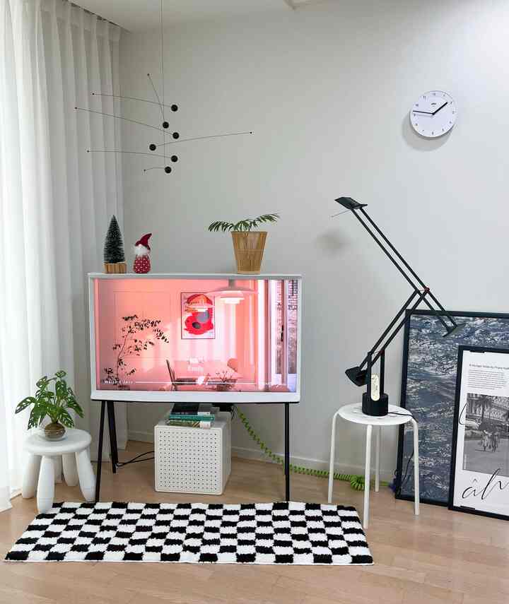 白と茶色のトーンのリビング、テレビ台やスツール、時計が配置されたミニマルでナチュラルなインテリア