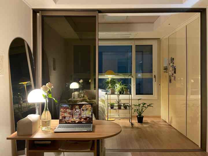 ウッドトーンと間接照明が調和するワンルームの寝室とリビング空間、引き戸と植物が落ち着いた雰囲気を演出