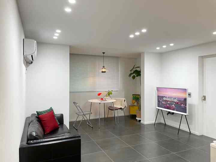 白と黒のトーンのリビング兼キッチンスペース、透明な椅子とダイニングテーブルが配置されたシンプルで落ち着いた雰囲気のインテリア