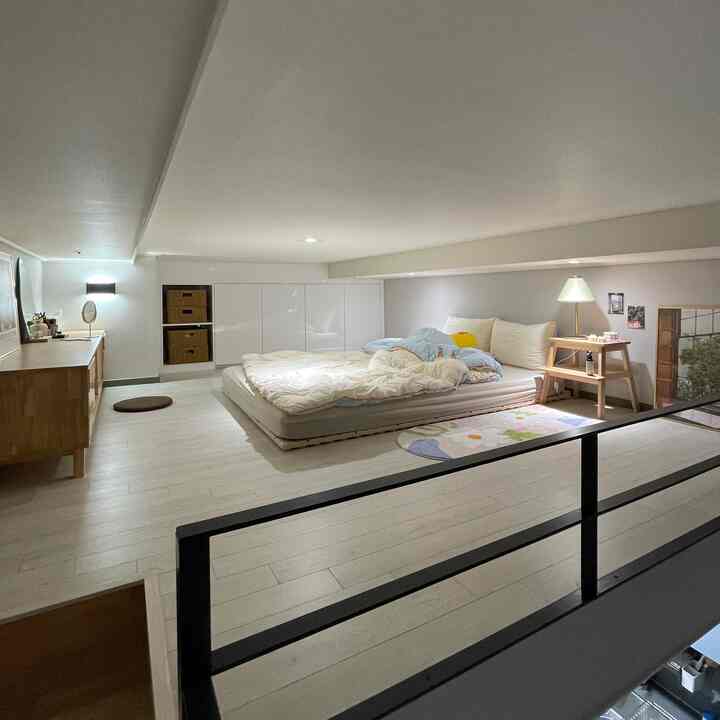 白と木目調が調和する低い天井のロフト寝室、シンプルな家具配置で落ち着いた雰囲気のあるインテリア