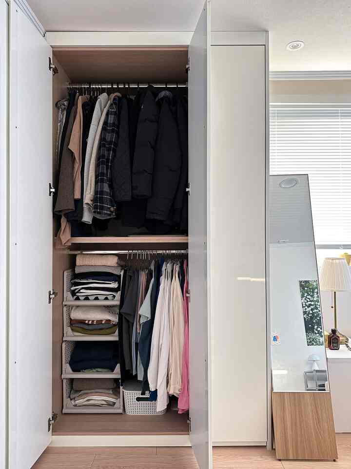 白いトーンの壁とビルトインクローゼット、整然としたリビングボックスが配置されたモダンな衣装部屋