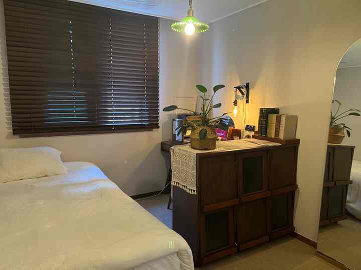 ナチュラルトーンの寝室、木製ブラインドと全身鏡が配置された印象的な空間