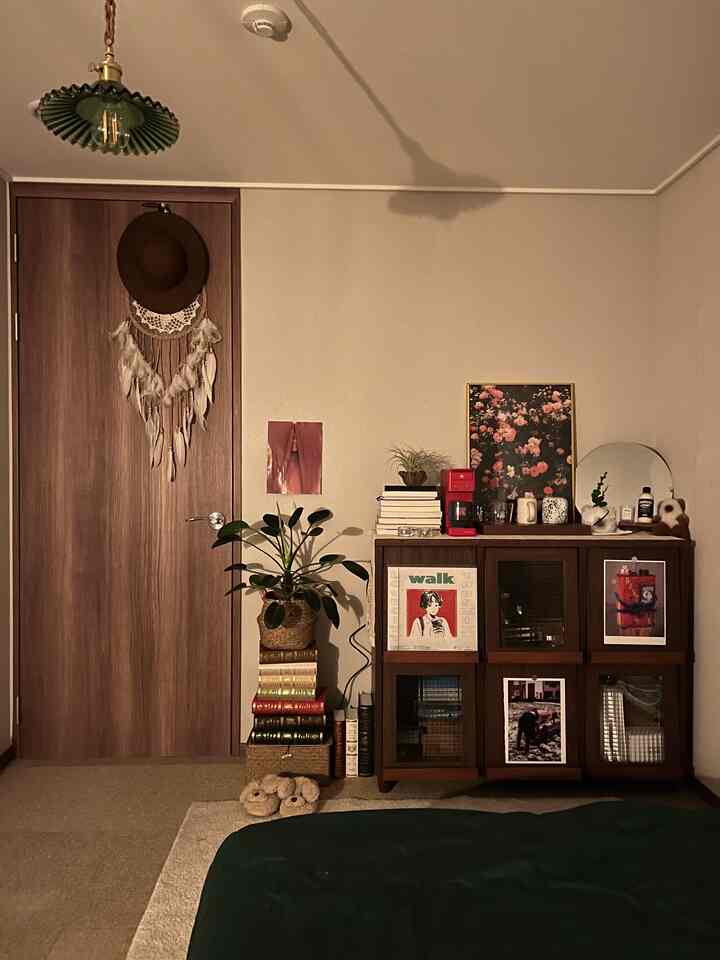 暖かいブラウンとナチュラルトーンの寝室、ウッドキャビネットにカフェ風アクセサリーとペンダントライトが配置された雰囲気のある空間
