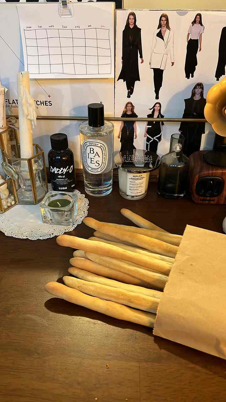 ベージュ調の小さなフォトゾーン、パンスティックとキャンドル、ディフューザー、木目調のオブジェが配置された雰囲気のある空間