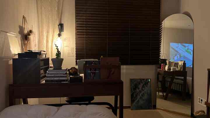 暖かい木目調とベージュトーンのワンルーム寝室、デスクとベッドが配置された居心地の良い自然なインテリア