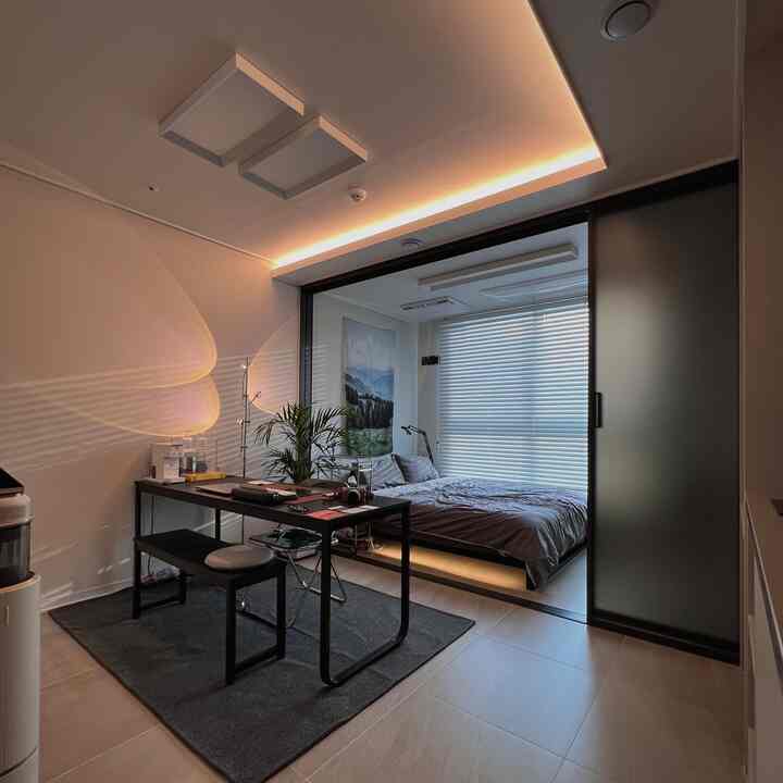 ホワイトとブラックの調和があるモダンな寝室とワークスペース、木製ブラインドとラグが配置された清潔感のある空間