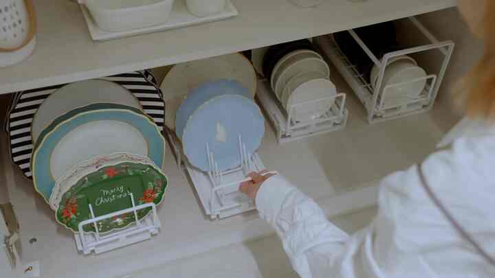 白を基調としたキッチン収納スペース、スライディング式の皿とボウルのオーガナイザーが整理された印象的な空間