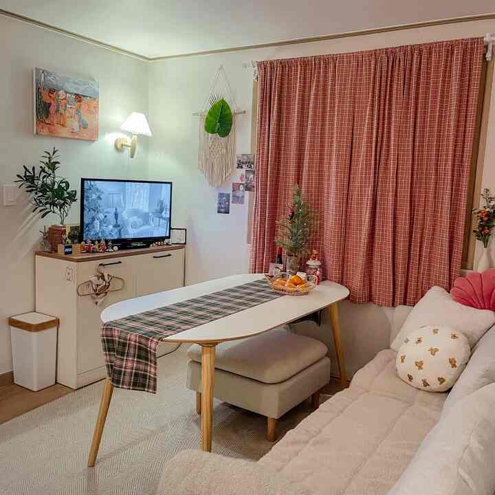 ナチュラルな色調のリビング。ベージュのソファ、テレビ台、チェック柄のカーテンとラグが配置された雰囲気ある空間