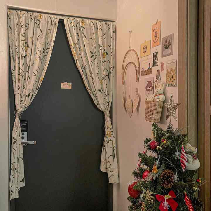 白とネイビートーンの玄関、花柄のカーテンと装飾されたクリスマスツリーが温かく居心地の良い雰囲気のインテリア