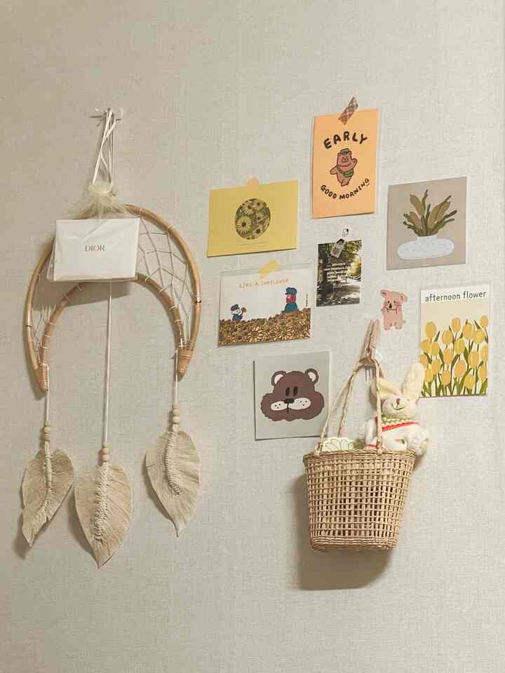 明るい黄色の壁にポストカードやドリームキャッチャー、ラタンバスケットが配置された暖かくナチュラルな玄関インテリア