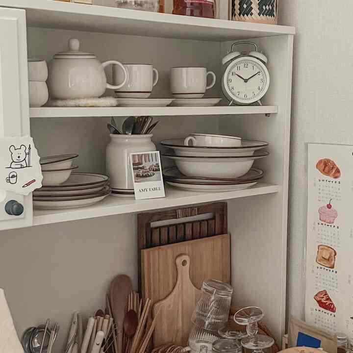 ブラウンのトーンのキッチン棚に皿や木のまな板、白い食器が整頓された雰囲気のあるキッチン