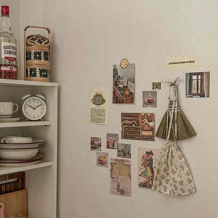 ベージュの壁紙があるキッチン空間、壁にヴィンテージ風のポストカードや小物が飾られた雰囲気のあるインテリア