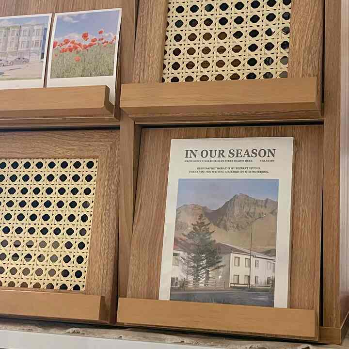 木目調のリビング、中央に靴箱と収納が配置され、ポストカードと額装アートが飾られた自然で居心地の良いインテリア