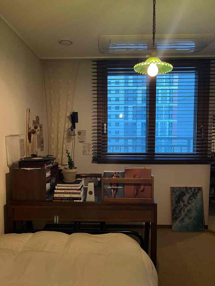 ナチュラルカラーの寝室、ベッド前に木製デスクとブラインドが配置された雰囲気のある空間