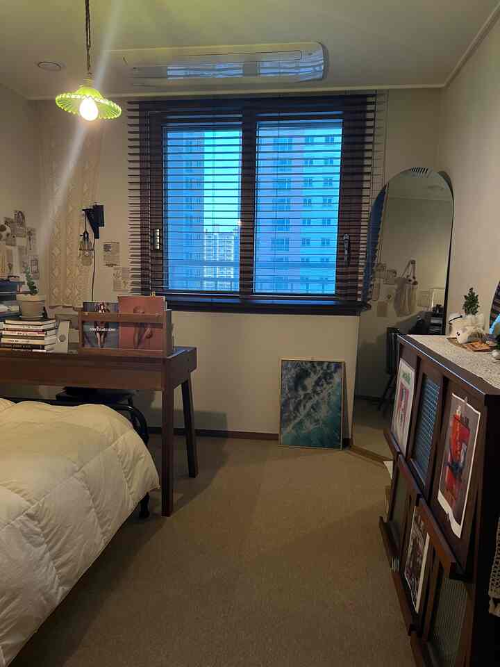 ナチュラルな木目調とベージュ色調の寝室、壁付けクローゼットと全身鏡、木製デスクが配置された落ち着いたインテリア