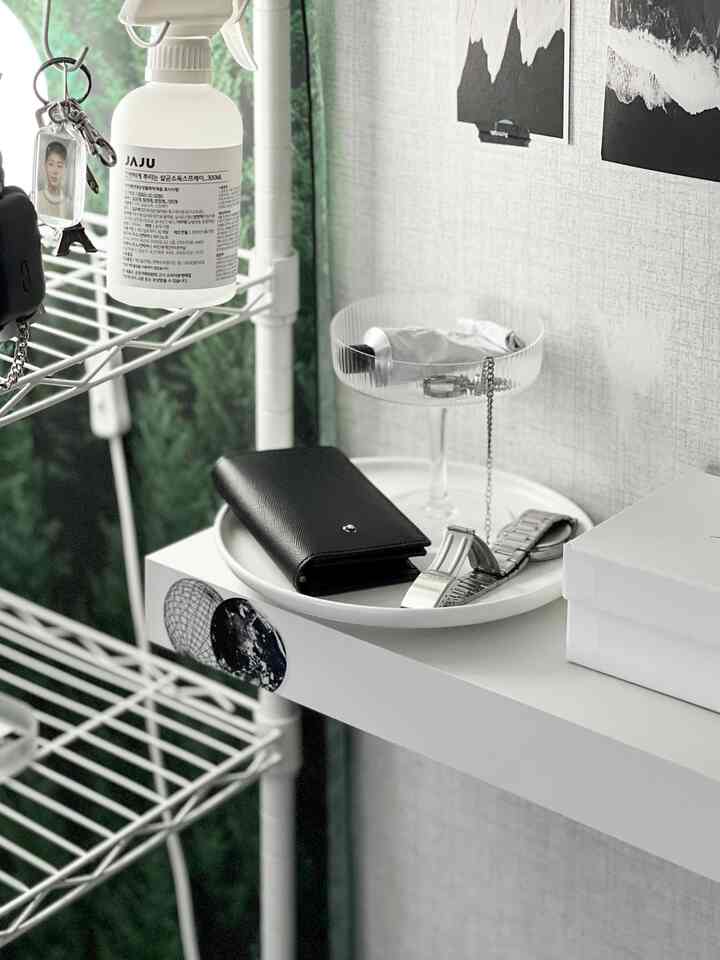 ホワイトとグレーの落ち着いたトーンのコンパクトな空間、棚と皿に日用品とアクセサリーが整理された雰囲気のあるインテリア