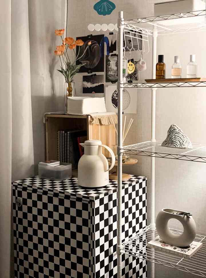 白と黒のチェッカーパターン家具と白い棚に花瓶とオブジェが配置されたシンプルでナチュラルな雰囲気のインテリア