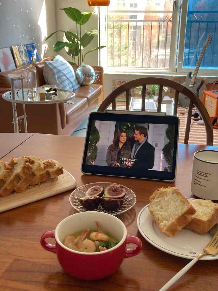 自然光差し込むブラウンの木製ダイニングテーブルがあるキッチン、レザーソファとリビングのインテリアが調和した雰囲気のあるホームパーティー空間